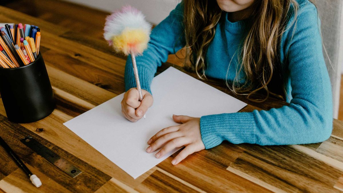 Un enfant dessine sur une feuille de papier