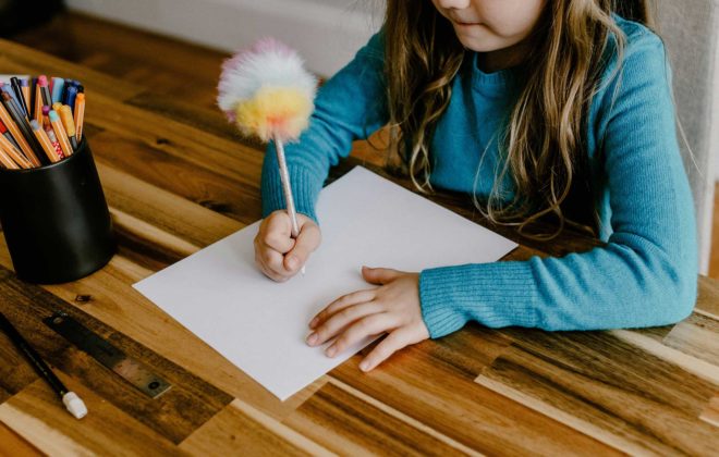 Un enfant dessine sur une feuille de papier